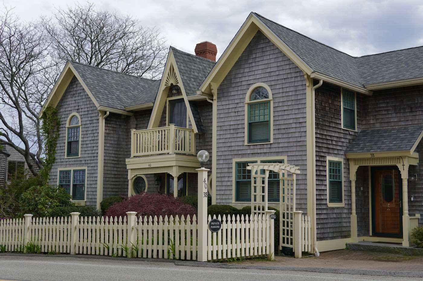 Cedar-shingled house behind a white picket fence