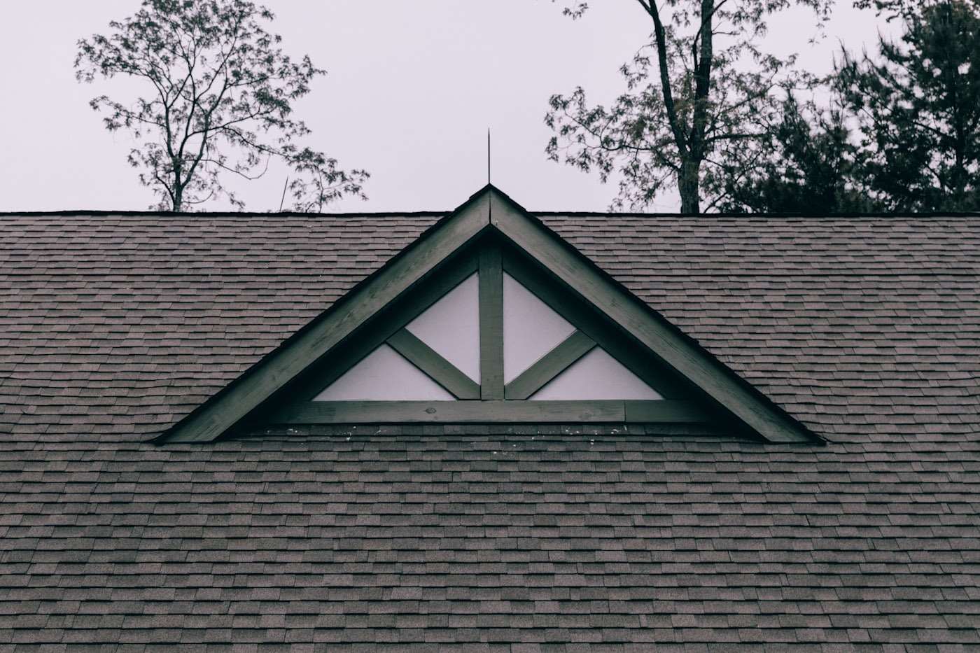 Gable end with a triangular attic window and dark shingles